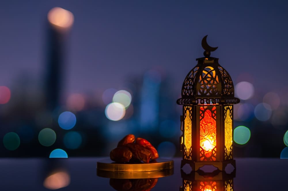 Ramadan Kareem lantern and dates fruit with city light background.