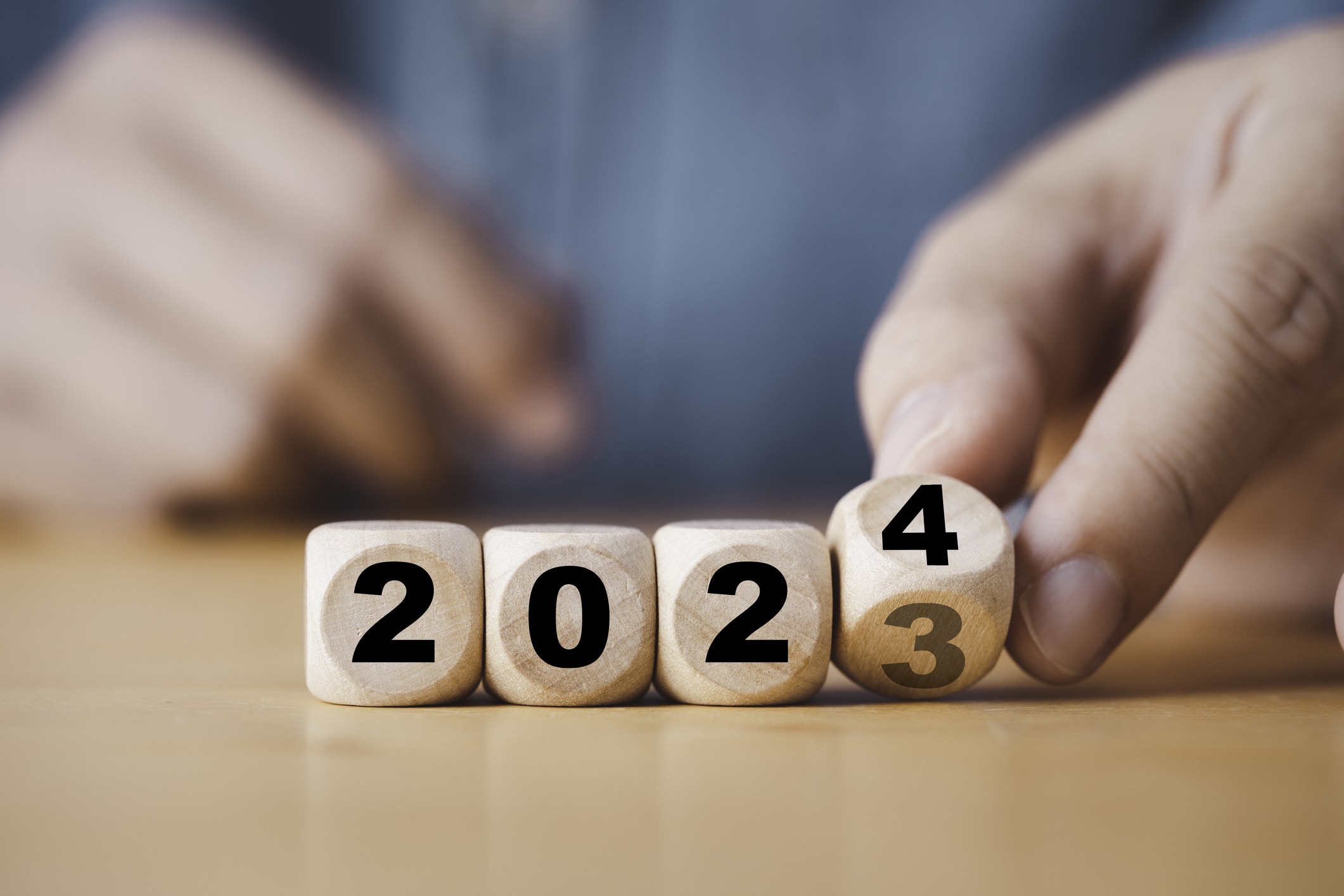 Hand flipping of 2023 to 2024 on wooden block cube for new year.